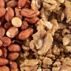 A detailed view of a healthy mix of raw peanuts and walnuts, highlighting texture and variety.
